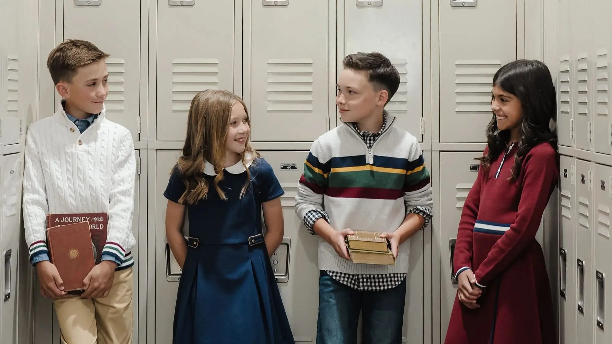 Four children standing in front of lockers, holding books.