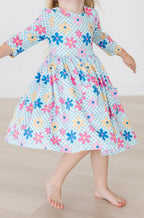 Child wearing a colorful floral dress on a plain background