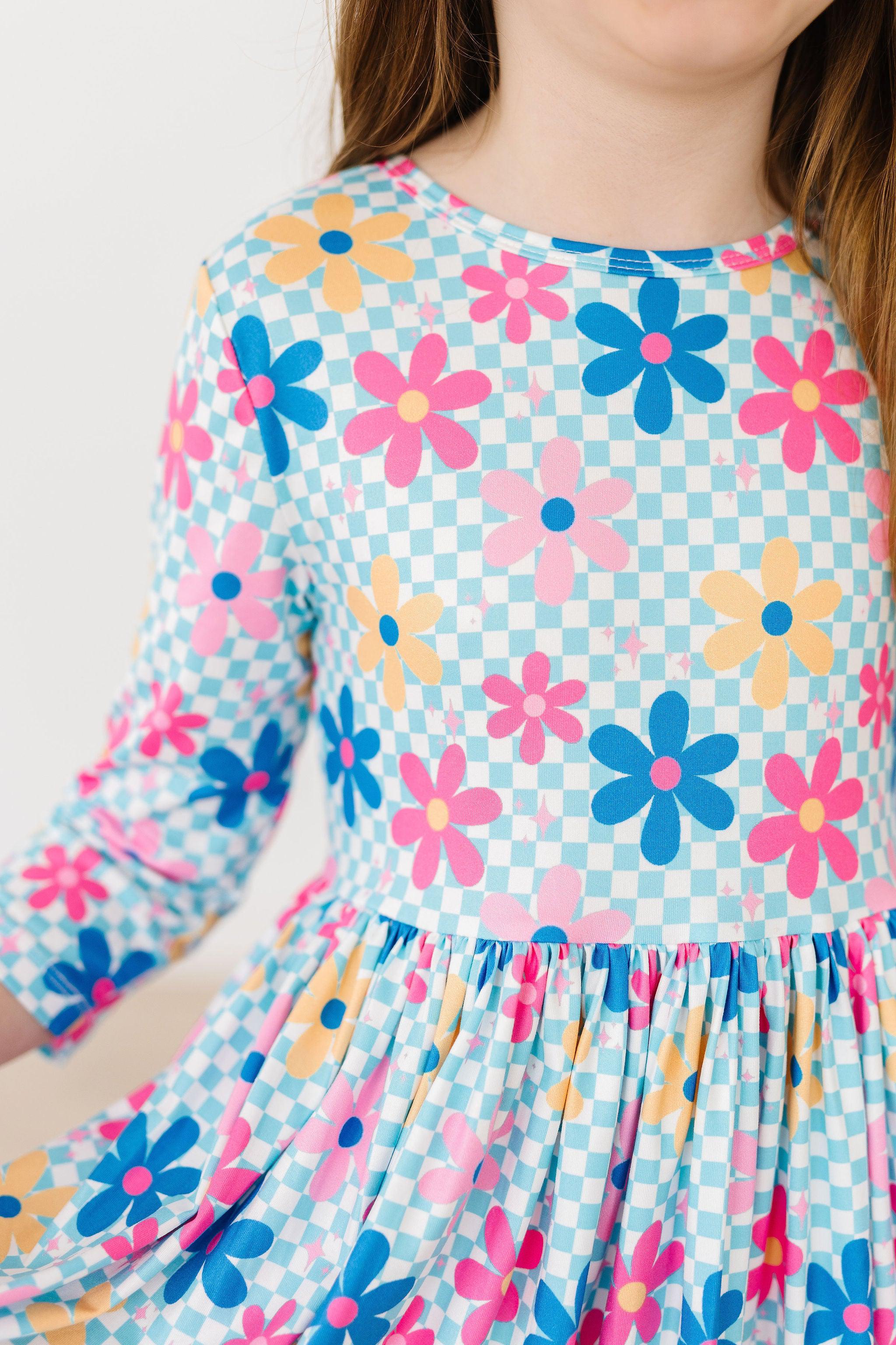Child wearing a colorful floral dress with a checkered pattern