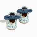 Pair of baby shoes with floral pattern and blue bows on a white background
