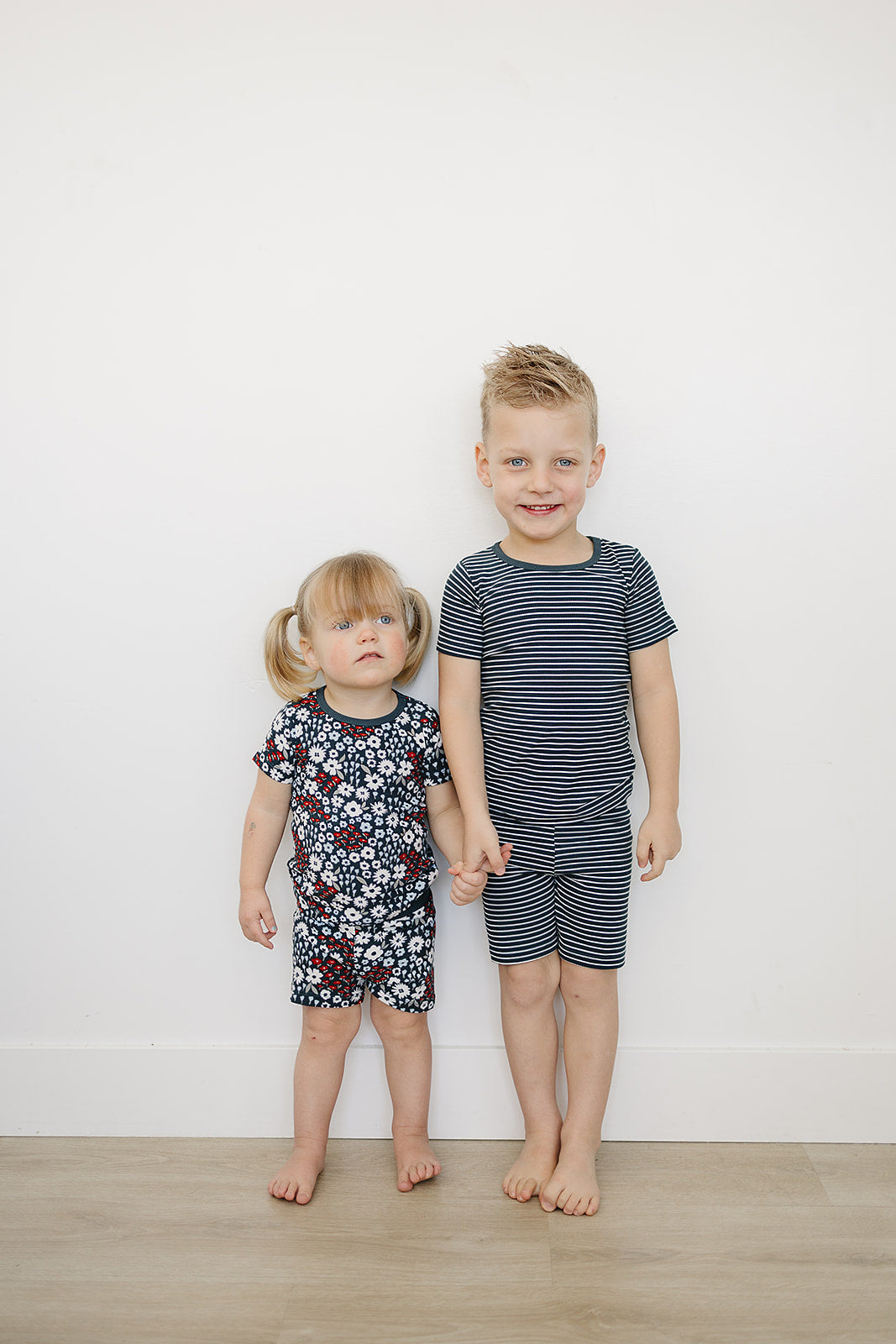 children wearing navy striped and floral americana bamboo print toddler short set against a white wall


