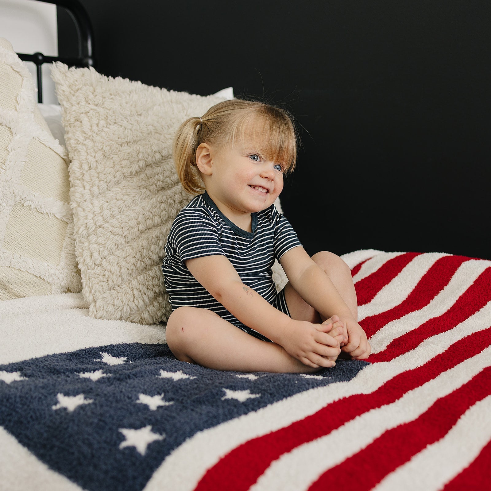 smiling girl wearing navy striped bamboo toddler short set in bedroom

