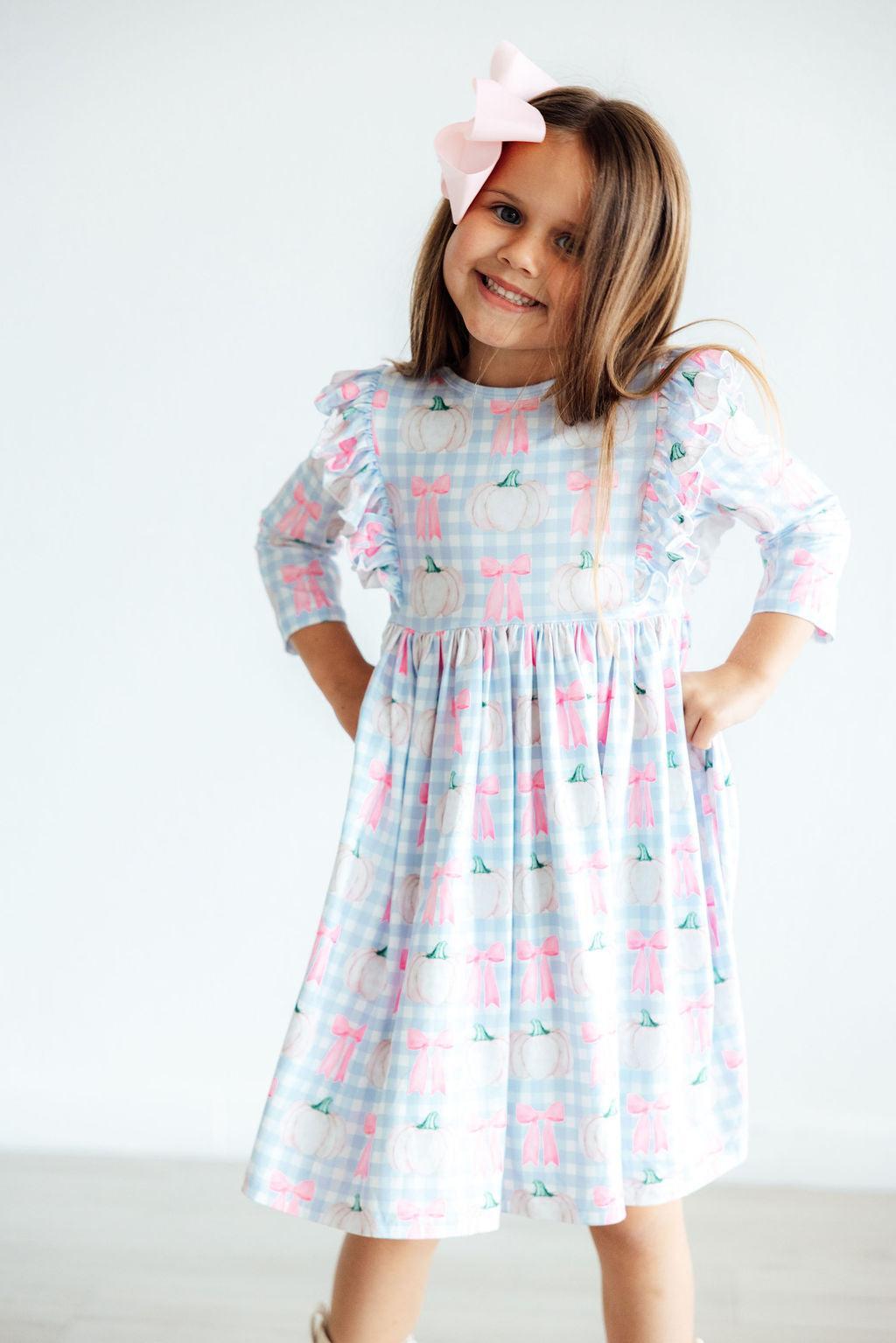 Young girl wearing a patterned dress with a white background