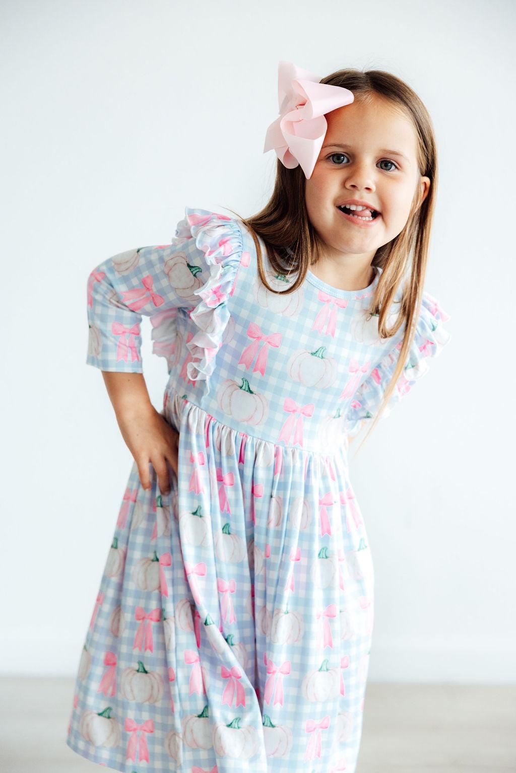 Young girl wearing a patterned dress with a white background