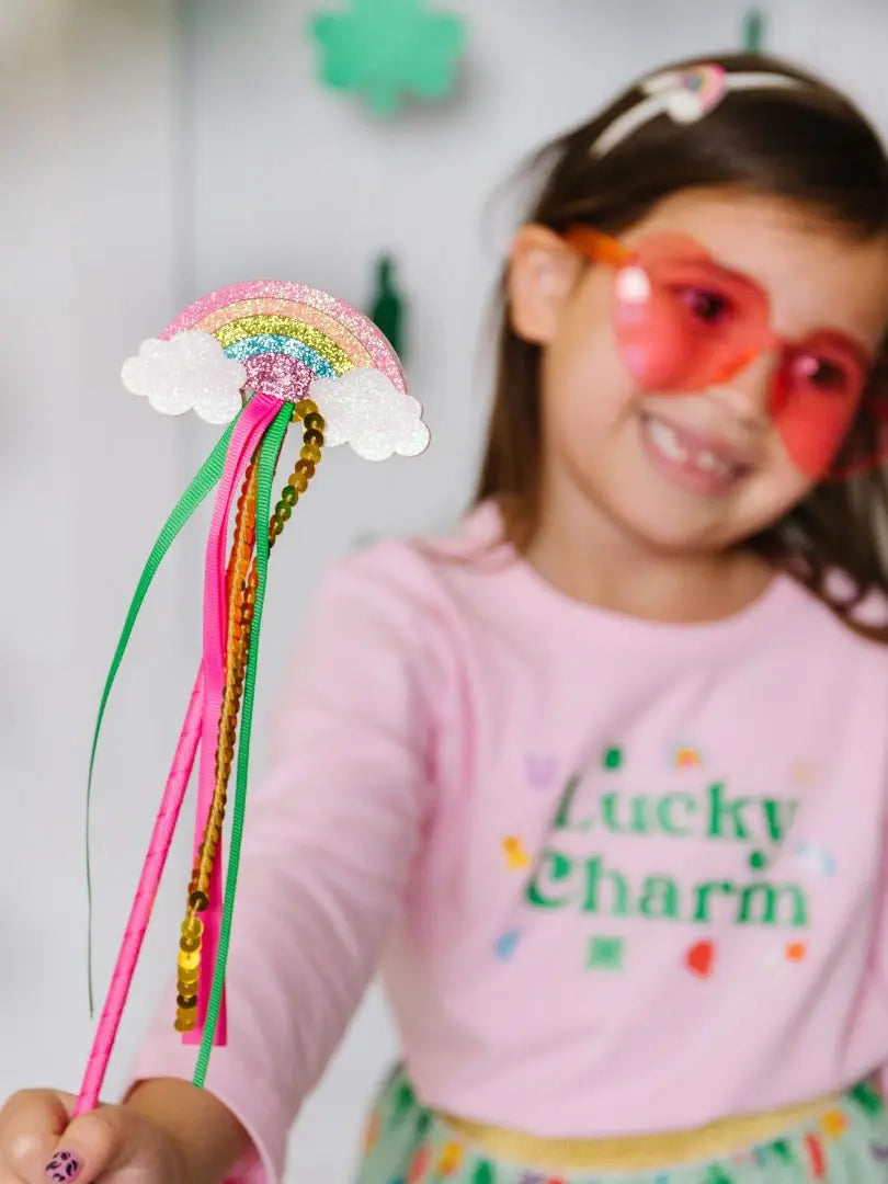 little girl dress with lucky charm tee and lucky charm tutu holding a rainbow wand 